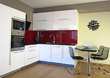 Obývací pokoj s kuchyní je navržen pro studentku, která si přála moderní černo bílou kombinaci nábytku ve vysokém lesku. Aby místnost nevypadala příliš neosobně, rozzářili jsme ji červenými doplňky.
